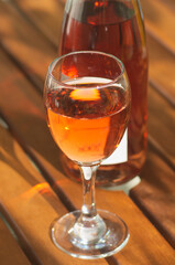 glass and bottle with rose vine on wooden table