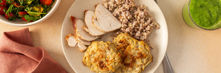 Green buckwheat, chicken breast, and zucchini pancakes served with fresh vegetable salads for a nutritious breakfast or lunch and celery cucumber smoothie, banner