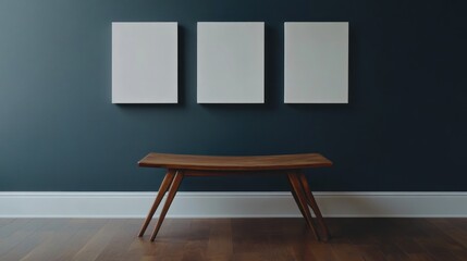 Three blank canvases on dark wall above wooden bench.