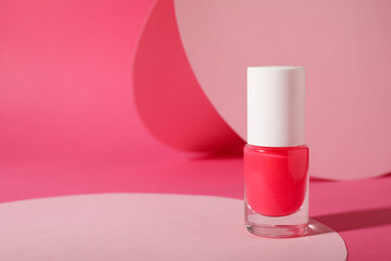 Nail polish in bottle on pink background, space for text