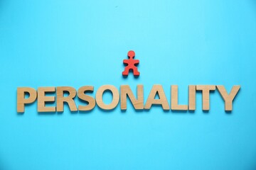 Word Personality made of wooden letters and red human figure on light blue background, top view