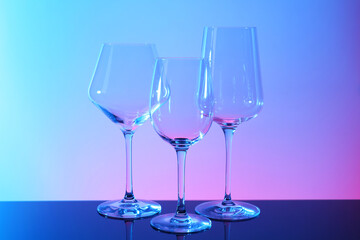 Empty glasses on table against color background