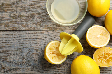 Plastic juicer and fresh lemons on grey wooden table, flat lay. Space for text