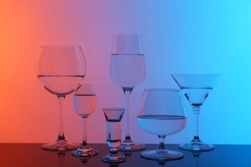 Different glasses with water on table, color tone effect