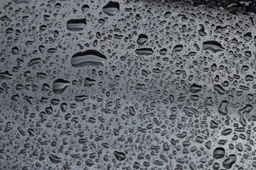 Water drops on dark grey glass surface, closeup