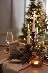Christmas place setting with festive decor on wooden table in room