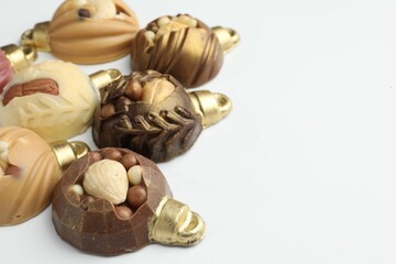 Delicious chocolate in shape of Christmas baubles on white background, closeup. Space for text