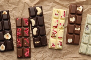 Different tasty chocolate bars on crumpled parchment, top view