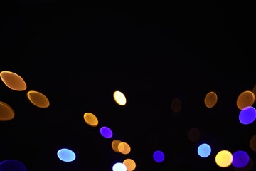 Blurred view of colorful lights on black background, bokeh effect