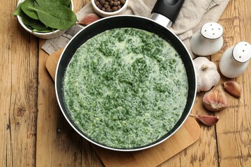 Delicious spinach sauce served on wooden table, flat lay