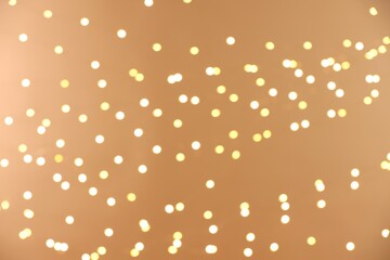 Blurred view of golden lights on light background, bokeh effect