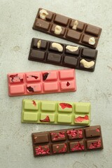 Delicious chocolate bars with different flavors on light table, flat lay