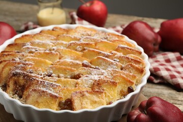 Delicious bread pudding with raisins, powdered sugar and apples on wooden table, closeup