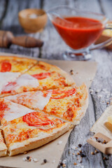 Hot tasty traditional various italian pizzas with salami, meat, cheese, onion, mushroom, tomatoes greens on a dark background