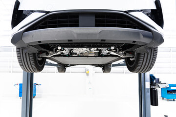 car at a service station on an electric lift , Bottom view of Electric car.