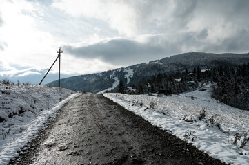 A winding road through a snowy mountain landscape, surrounded by frosty trees and serene winter...