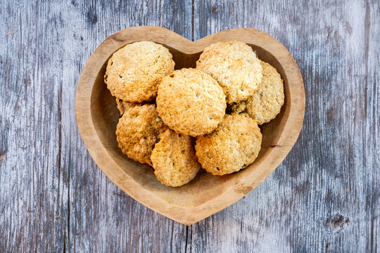A heart shaped wooden dish with home baked biscuits seen from above