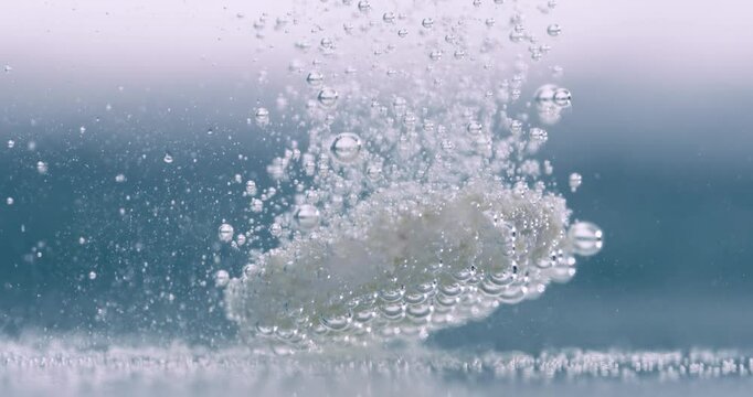 Extreme Close-up effervescent tablet, pill bubbling underwater. Shot on super slow motion camera 1000 fps.