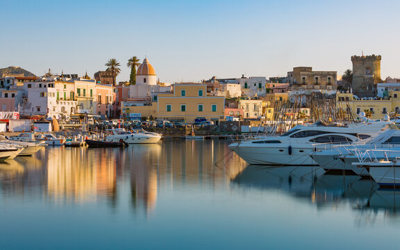 Ischia, Italy - April 20, 2018: Sunset view of Forio, Ischia island, Italy. Town streets with church, castle of Forio are reflected in serene sea. 