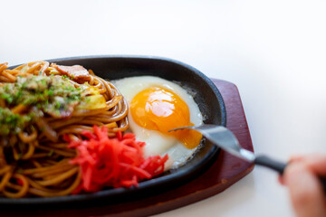 焼きそばの目玉焼きをフォークで刺す