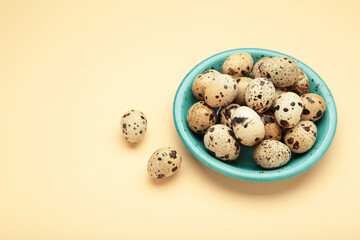 Quail eggs in bowl on beige background.