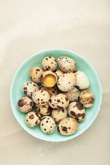 Quail eggs in bowl on light background. Vertical photo