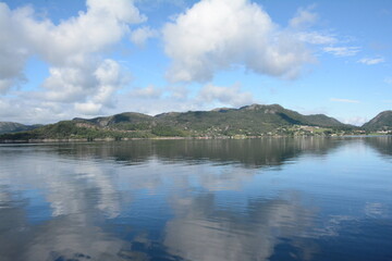 River view of land, from a boat, on sunny summer day with fluffy white clouds.