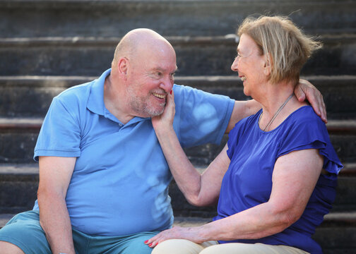 senior cheerful couple in love sitting on stairs  on summer day resting and bonding