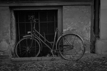 an old rusty bicycle leaning against an old house wall