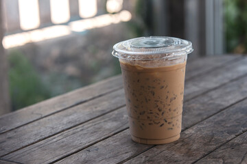 Iced coffee in a plastic cup lies on the table in a coffee shop bokeh background.