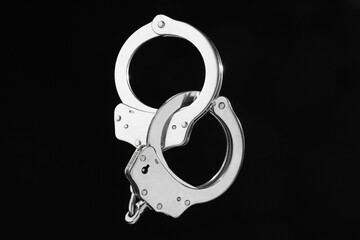 Metal chain handcuffs on black background, closeup