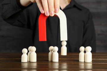 Woman with magnet attracting piece among wooden ones at table, closeup