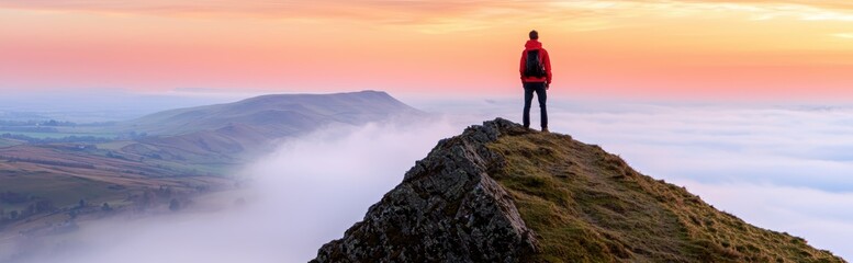 Obraz premium Hiker on Mountain Peak at Sunrise with Misty Valley Below