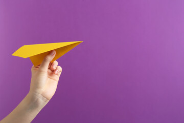 Woman with yellow paper plane on purple background, closeup. Space for text