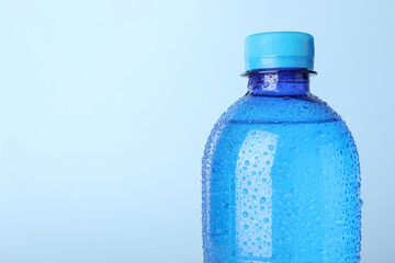 Naklejka premium Plastic bottle of water on light blue background, closeup. Space for text