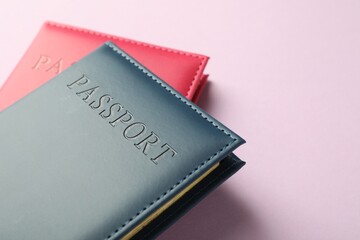Passports in color covers on pink background, closeup. Space for text