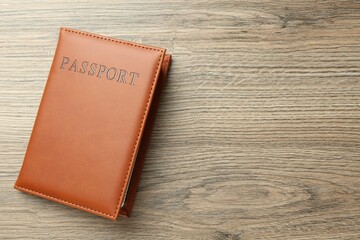 Passport in brown cover on wooden table, top view. Space for text