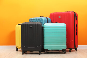 Many colorful suitcases on floor near orange wall