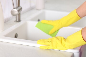Woman cleaning sink with rag in kitchen, closeup. Space for text