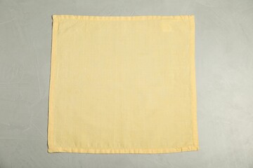 Pale yellow napkin on light grey table , top view