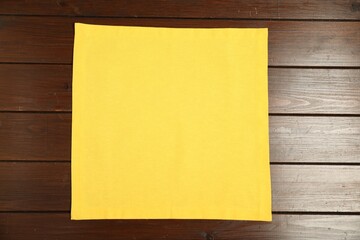 Yellow napkin on wooden table, top view