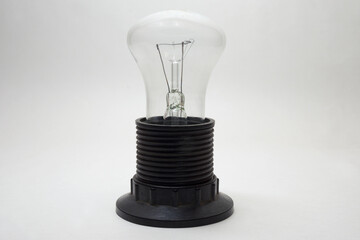 incandescent light bulb, mushroom shape (flat top). installed in medium size black plastic lampholder with shade ring on end of threaded shell