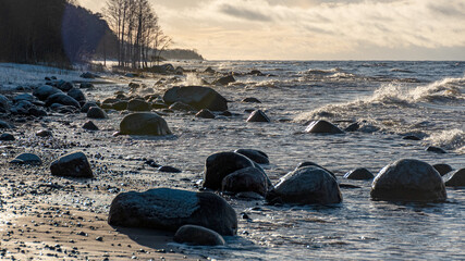 landscape with the seashore, windy winter day, water splashes, icy stones on the seashore, Baltic...