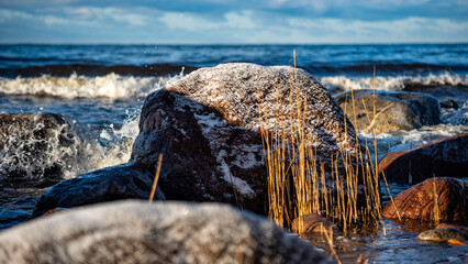 landscape with the seashore, windy winter day, water splashes, icy stones on the seashore, Baltic...
