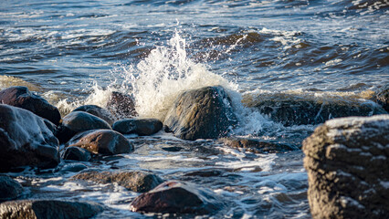 landscape with the seashore, windy winter day, water splashes, icy stones on the seashore, Baltic...