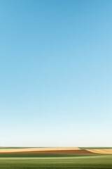 Vast landscape with vibrant fields under bright blue sky, serene