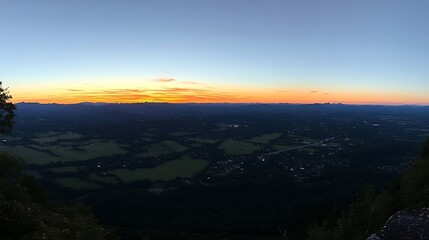 Fototapeta premium Panoramic sunset view from mountaintop overlooking valley farmland