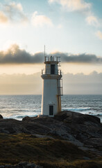 Faro en la costa al lado del mar en el atardecer con nubes