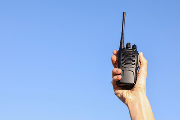 Woman with walkie talkie against blue sky outdoors, closeup. Space for text