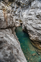 Arroyo con cascada con agua azul entre rocas de un desfiladero